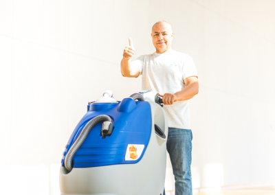 A surface technician cleaning the hall of a building with a scrubber-dryer